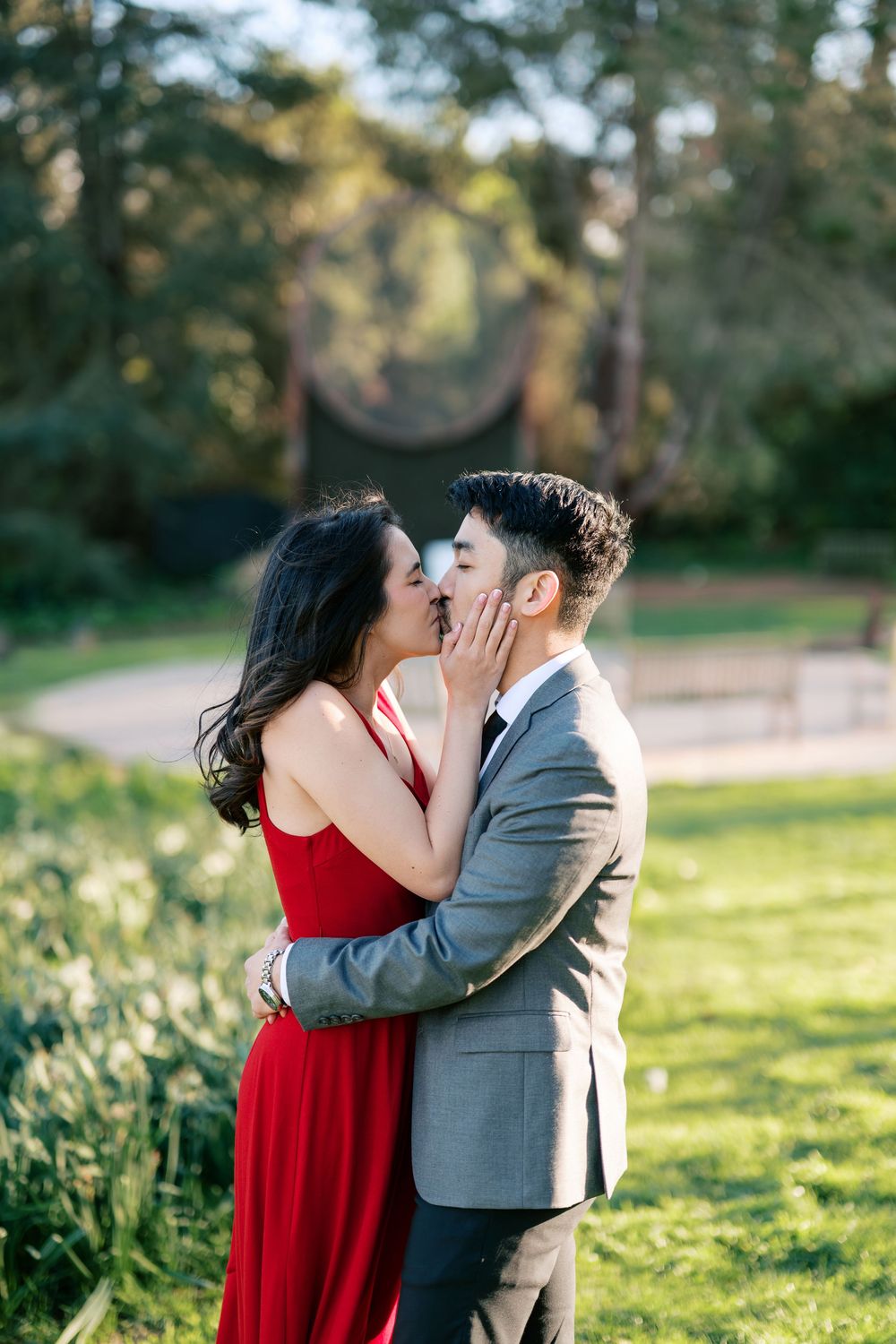 A romantic moment captured between a couple in formal attire embracing in a sunlit garden.