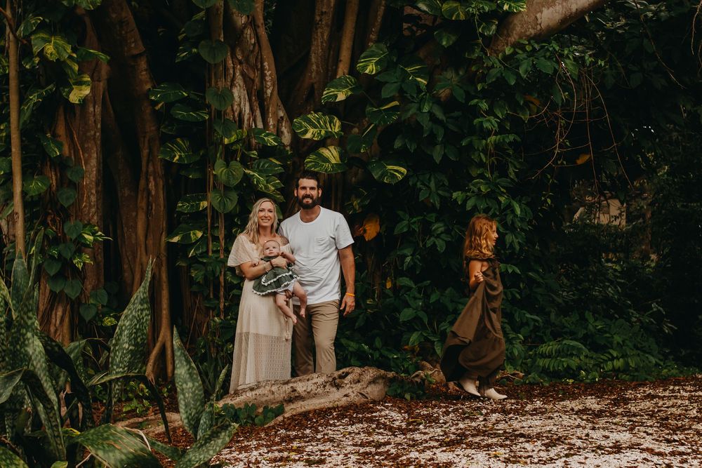 A couple walks together through a lush forest path during a romantic outdoor photoshoot session.