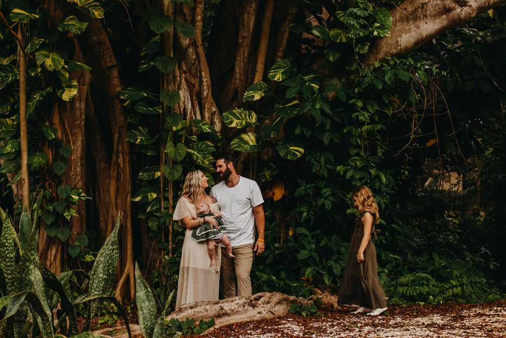 A romantic couple embraces in a lush tropical forest setting during a photo session.