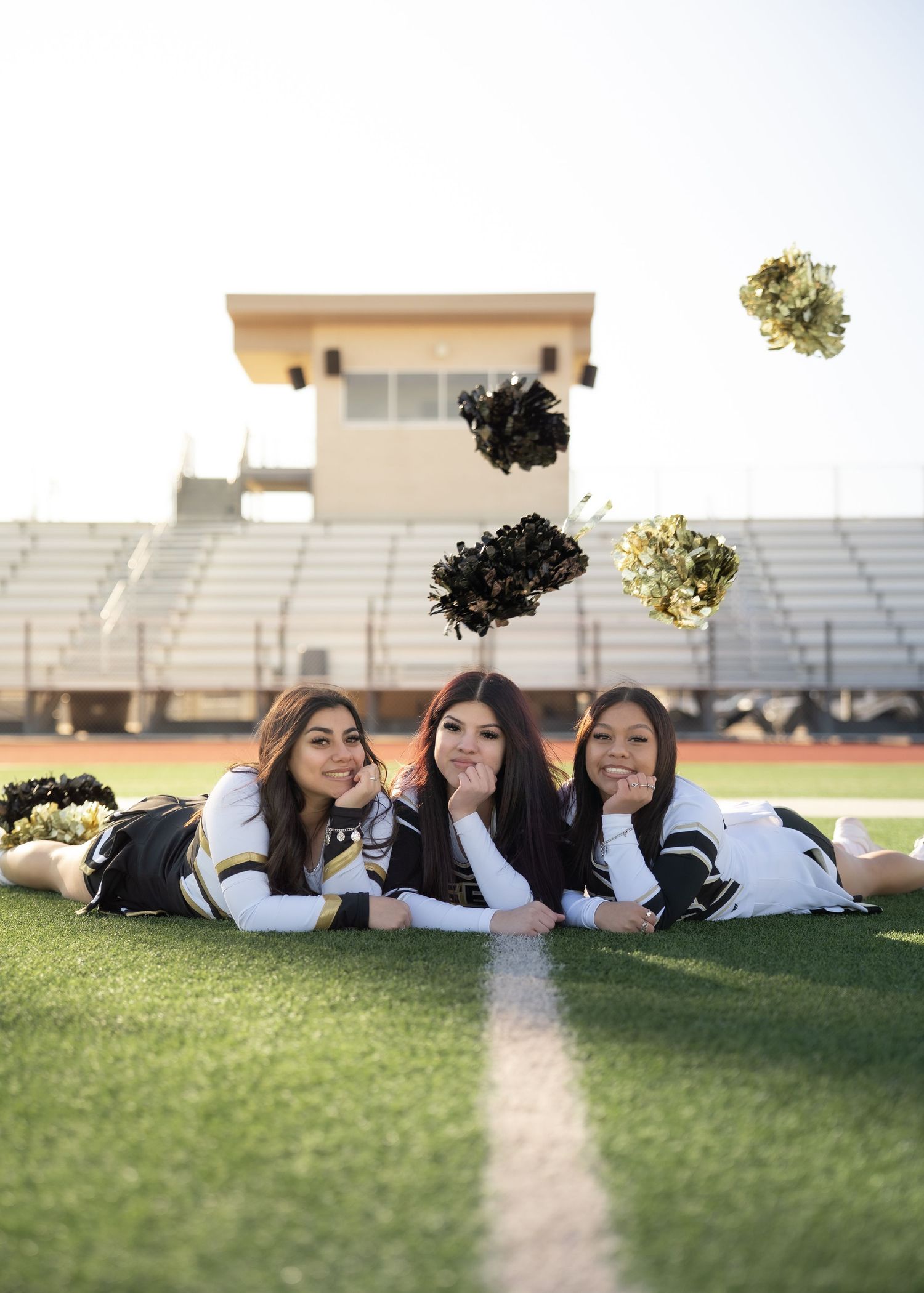 Cheerleaders tossing pom-poms in the air during outdoor group portrait