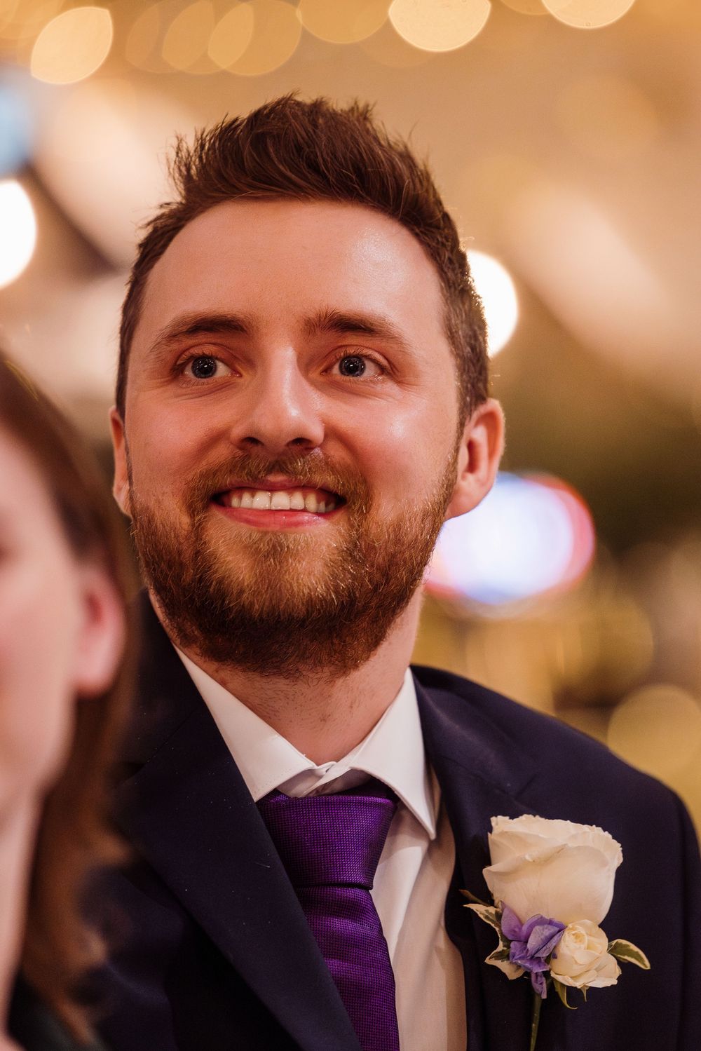 A sequence of close-up shots showing a groom in formal attire with a purple tie and white boutonniere.