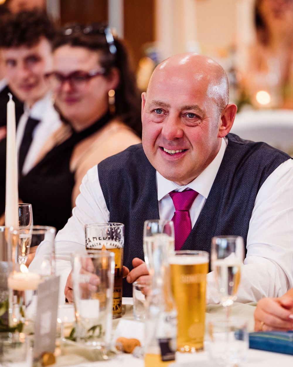 A group of people dining at a formal event with beers and wine glasses on the table.
