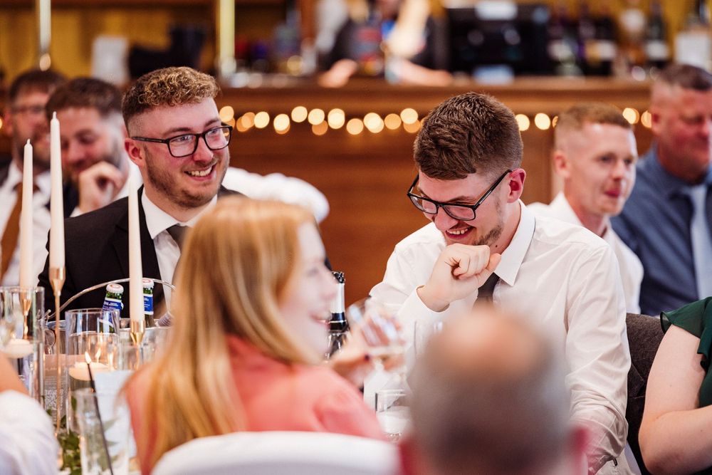 Wedding reception guests seated at tables with glowing lights and decorations creating a warm ambiance.