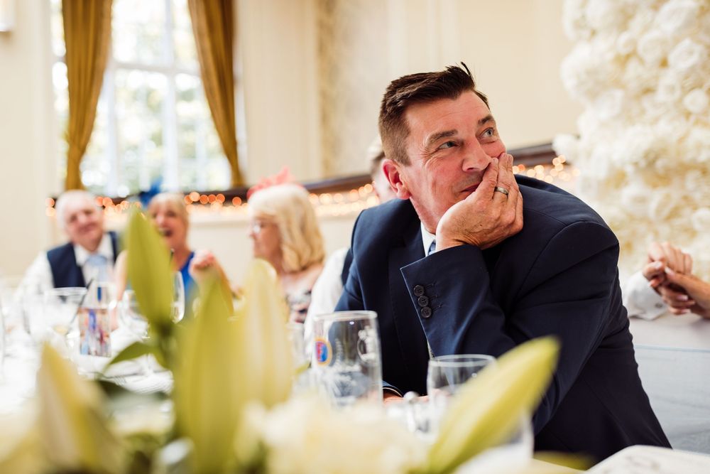 A group of people in formal attire laugh and smile during a celebratory dinner event.