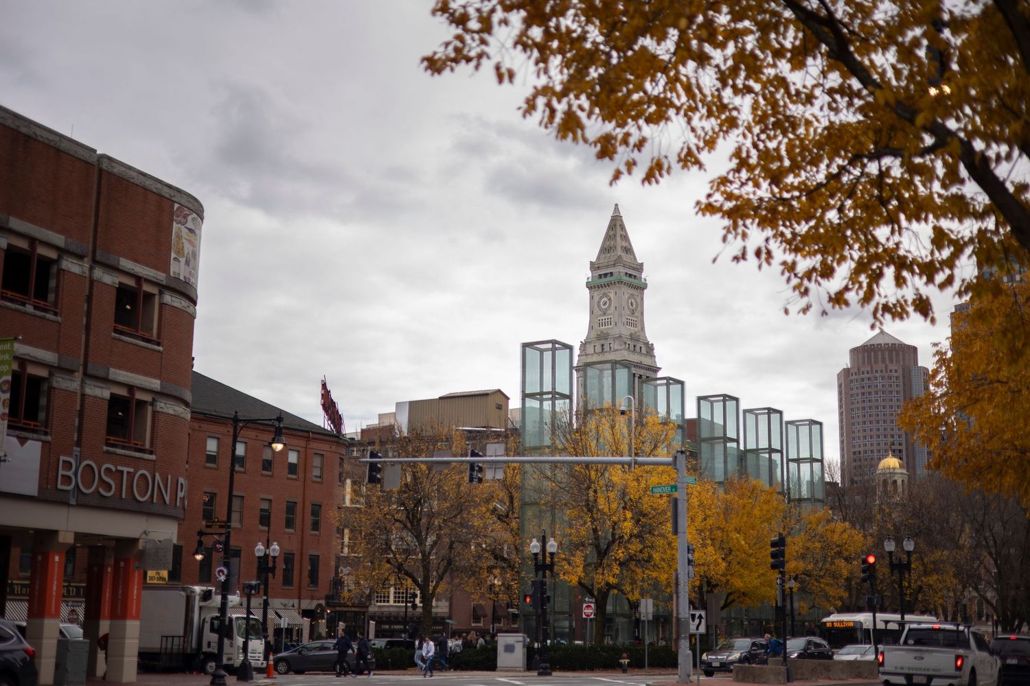 Historic brick buildings line a street in downtown Denver with autumn trees and the iconic clock tower in the distance.