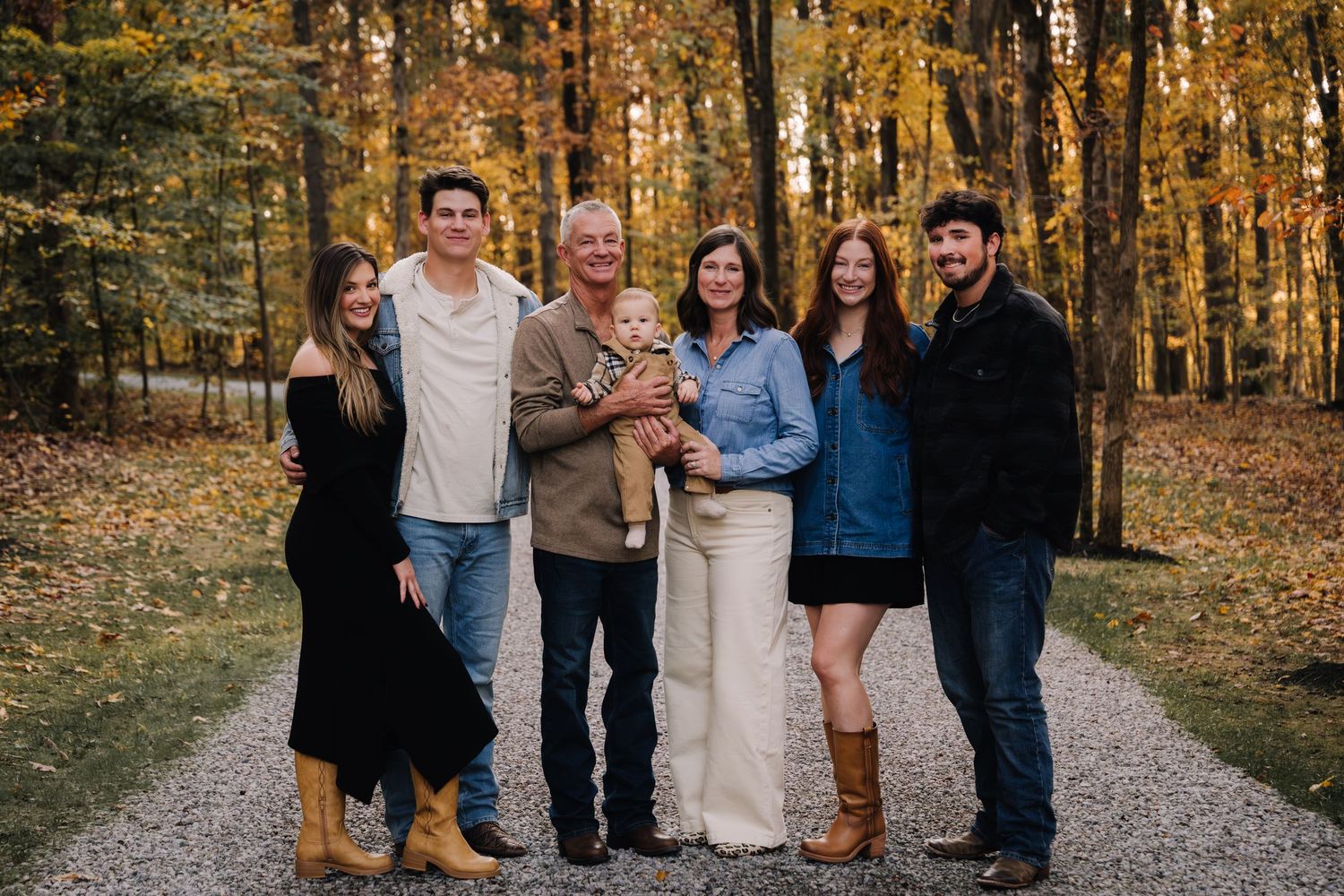 Group of people walking together on a tree-lined path during autumn with golden foliage in the background. Family photographer in Middle Ten