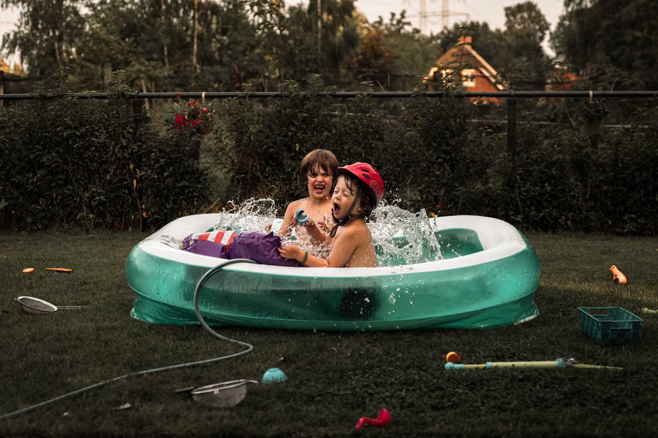 Two people relax in an inflatable pool during a warm summer evening in a backyard setting.
