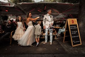 Wedding guests dance and celebrate under outdoor tent canopies at a lively evening reception.