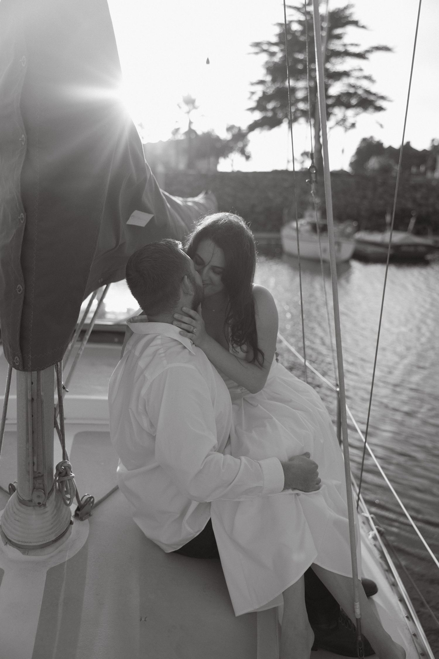 Black and white engagement photo of a couple kissing on a sailboat in Ventura
