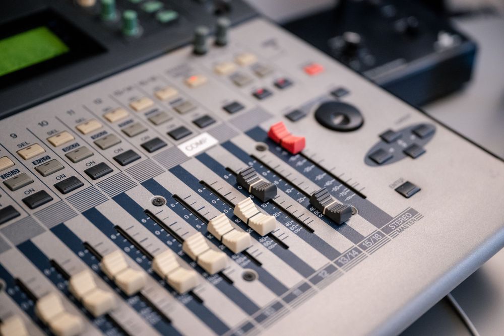 Digital audio mixing console with multiple faders and control buttons.