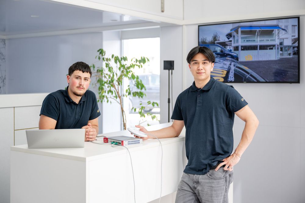 Team members posing at modern white office counter with architectural display on wall.