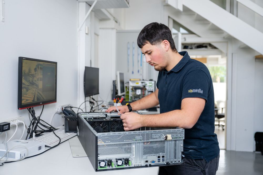 Technician working on audio equipment maintenance at white workstation.