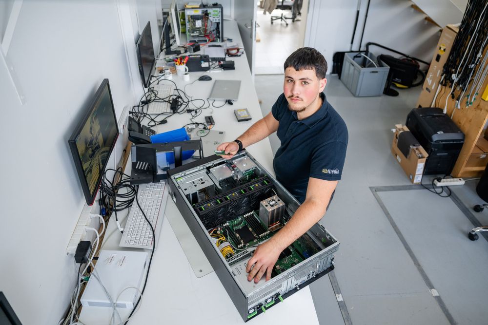 Technician repairing electronic equipment at workbench in modern office space.