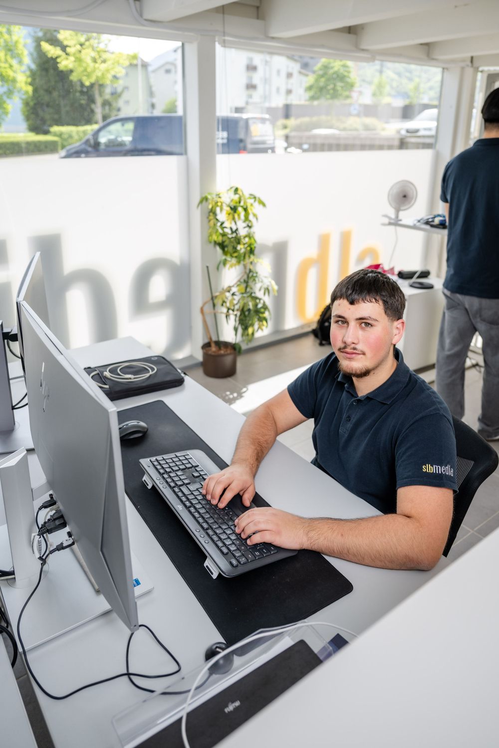 Employee working at computer desk in bright modern office space.