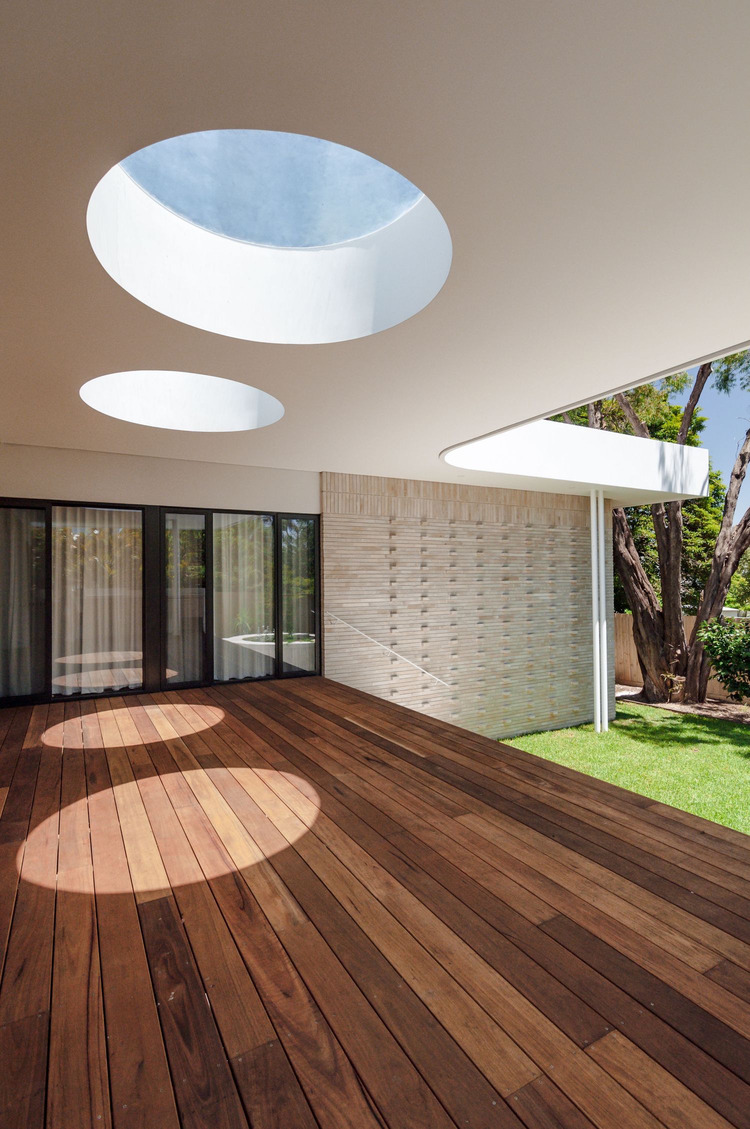 Luxury deck space with circular skylights and wooden flooring extending to a garden area.