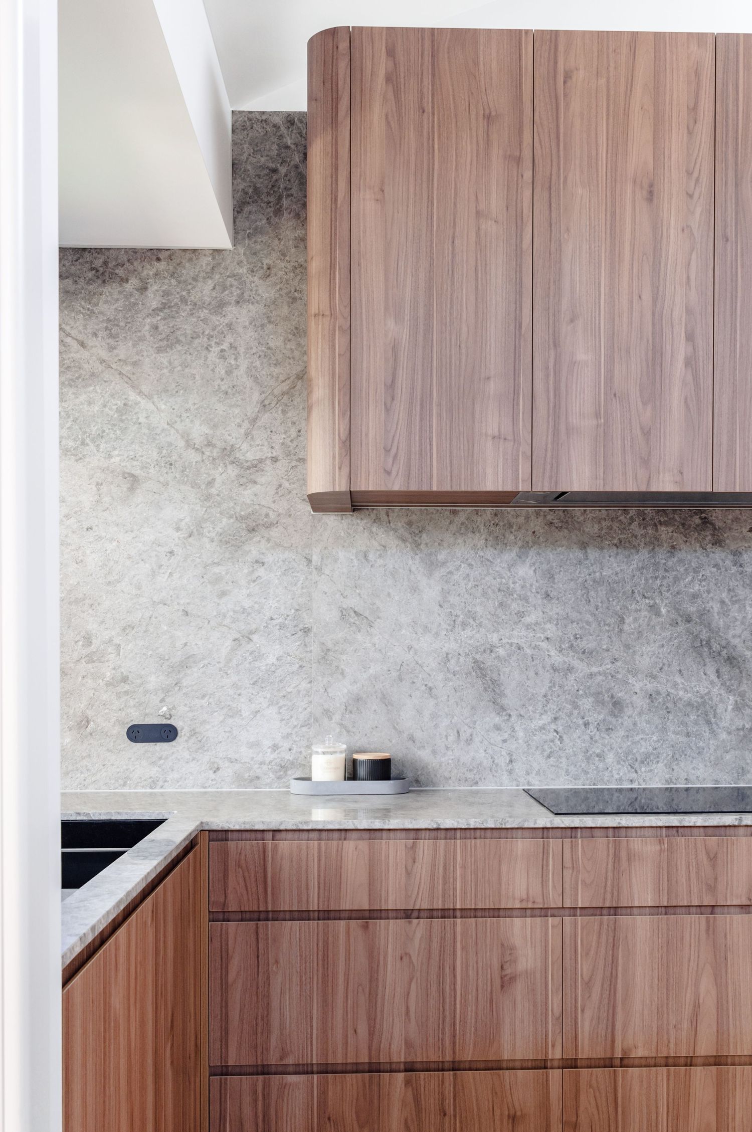 Close-up of modern kitchen cabinetry featuring wood grain patterns and marble backsplash.
