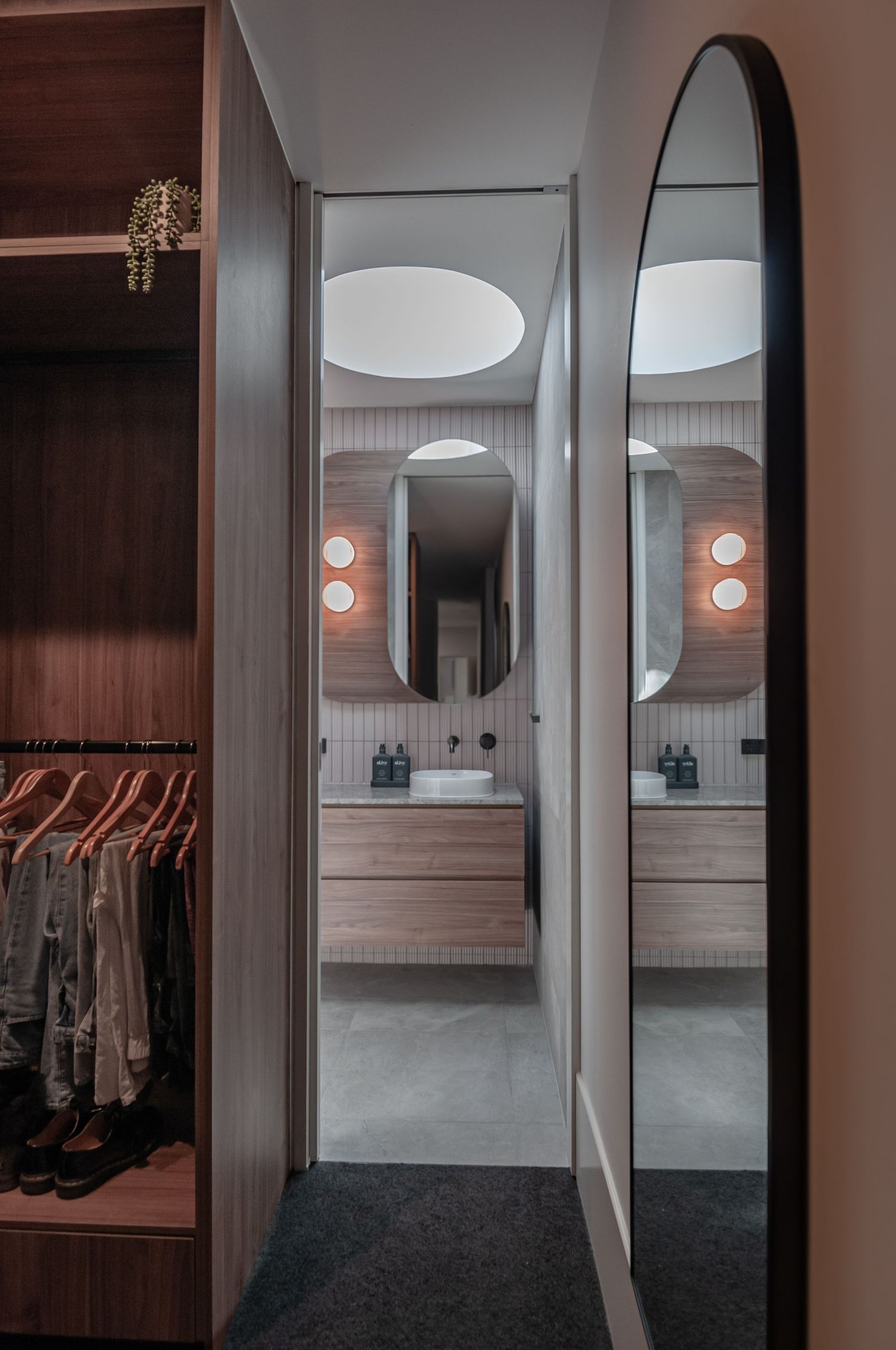Bathroom entryway with mirrored walls, wood paneling, and built-in closet storage.