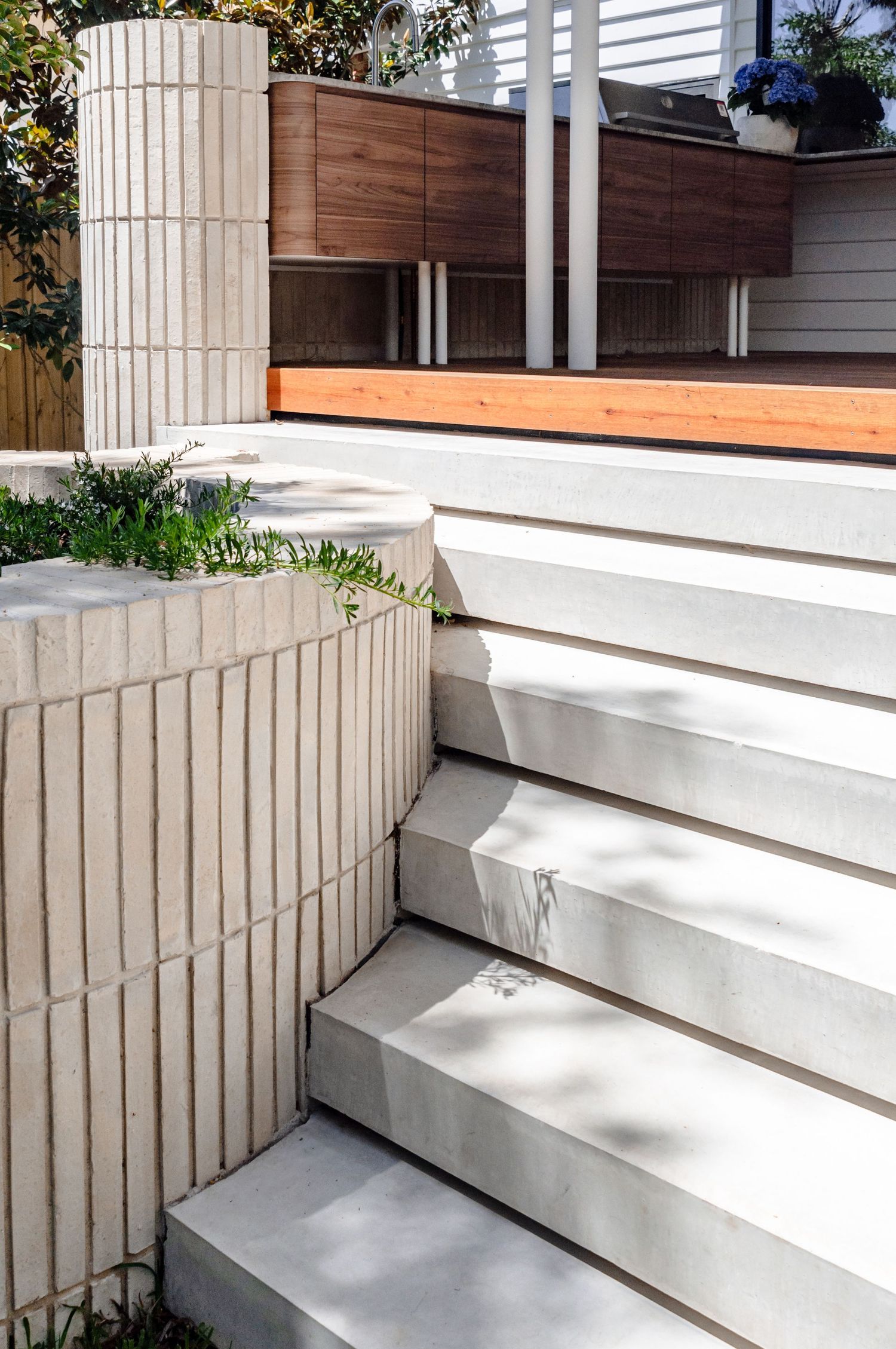 Modern architectural design featuring concrete steps and wooden deck with vertical textured walls.