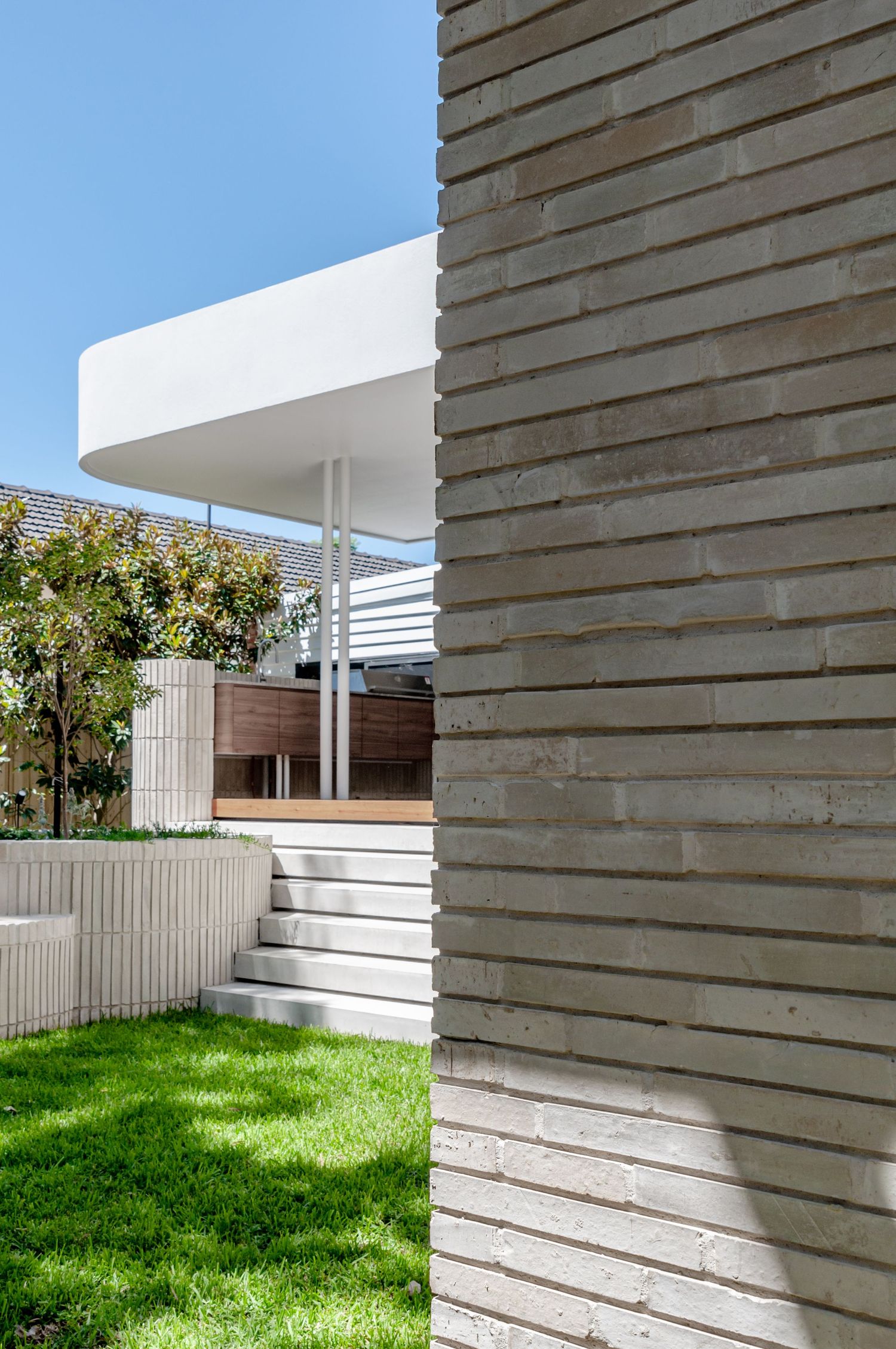 Modern exterior featuring textured concrete walls, white steps, and cantilevered roof design.