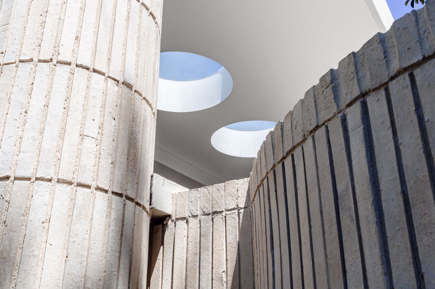 Interior architectural detail with cylindrical concrete columns and circular skylights.