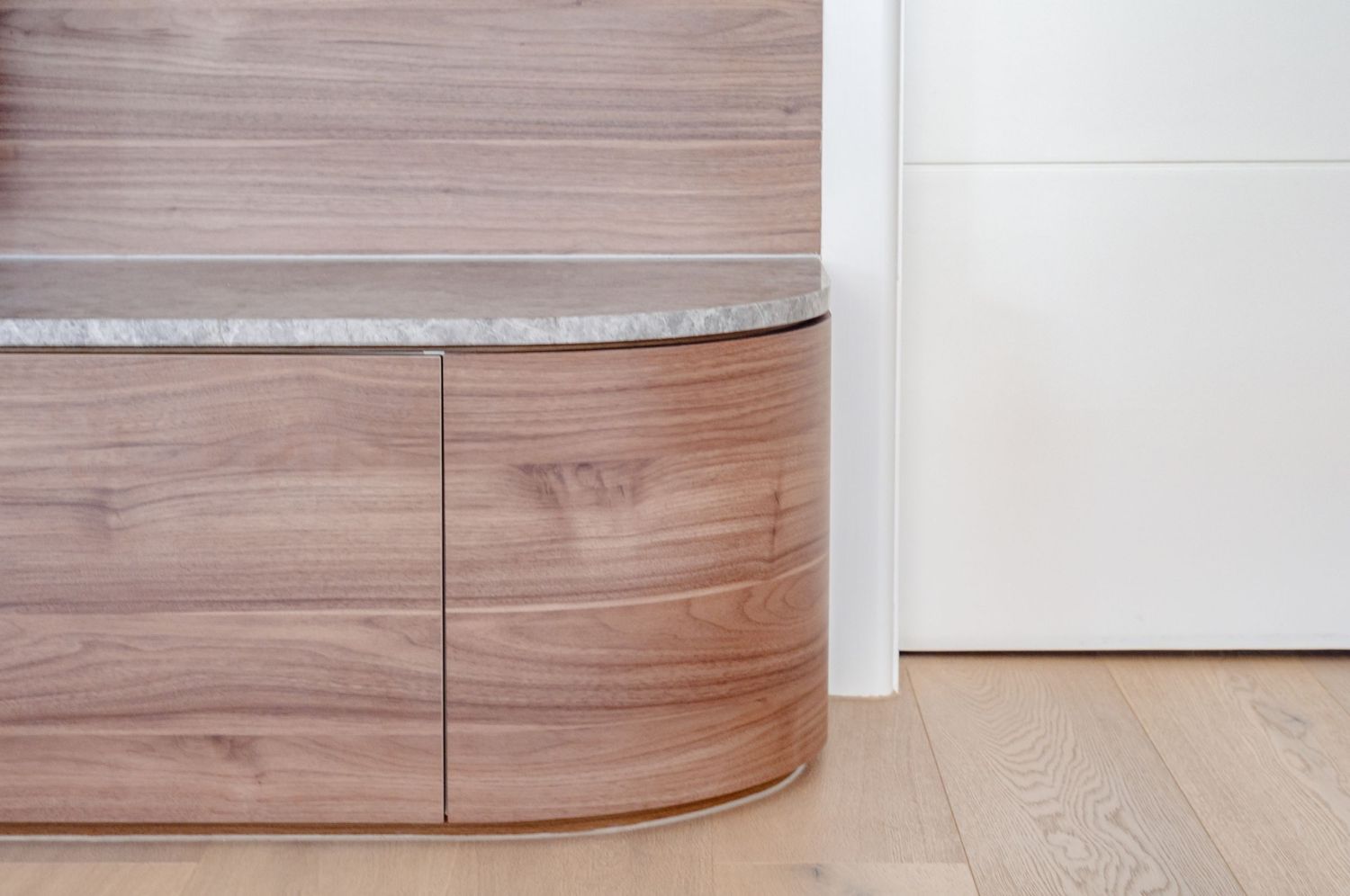 Close-up of curved wooden cabinet base with seamless joinery.
