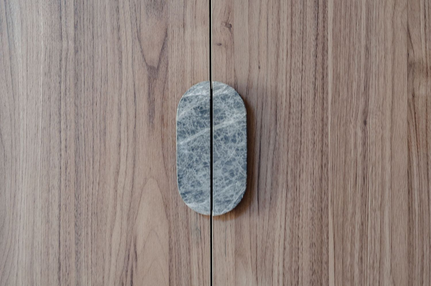 Natural stone door handle mounted on wooden cabinet panels.