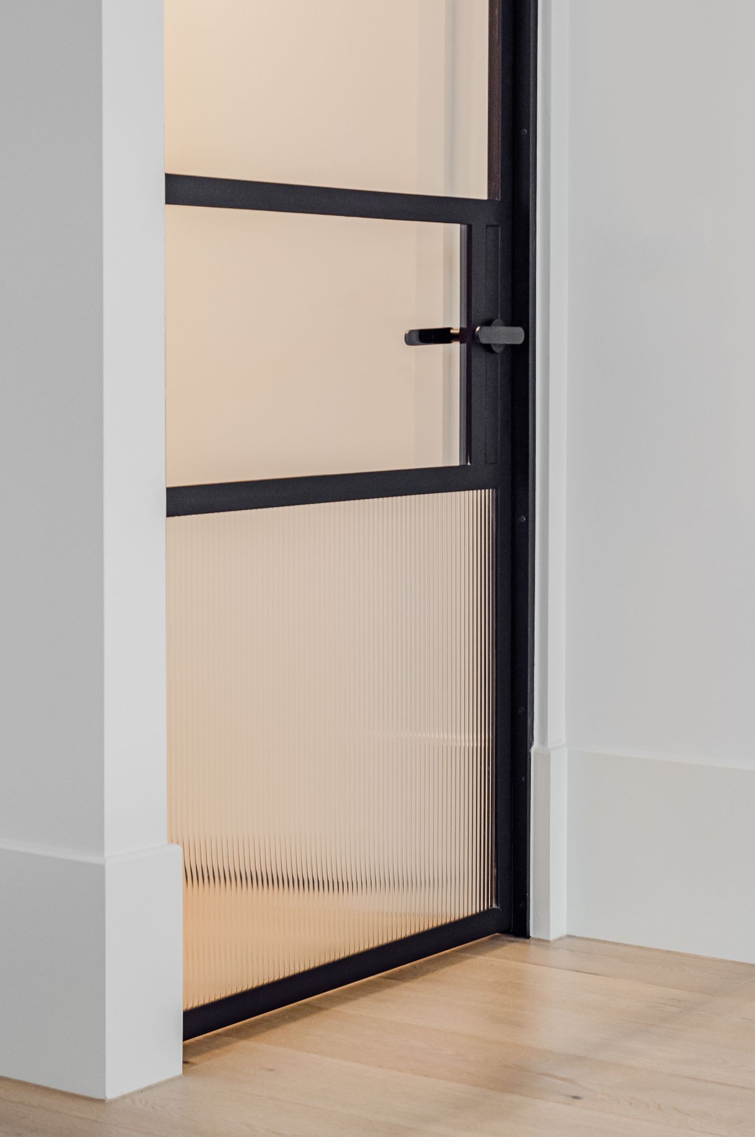 Modern black-framed door with ribbed glass panel and minimal hardware.