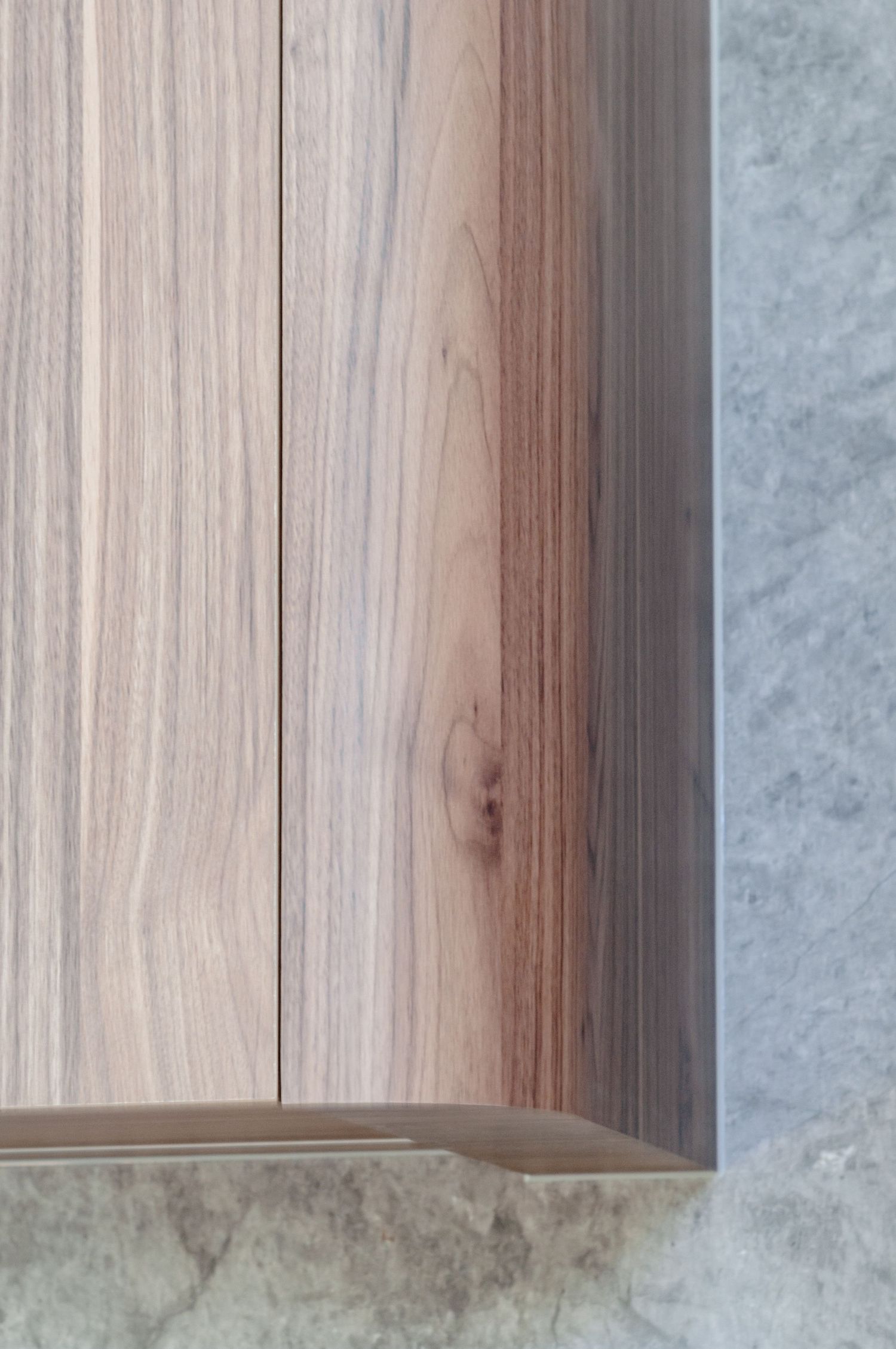 Detail of wooden cabinet panel meeting textured stone surface.