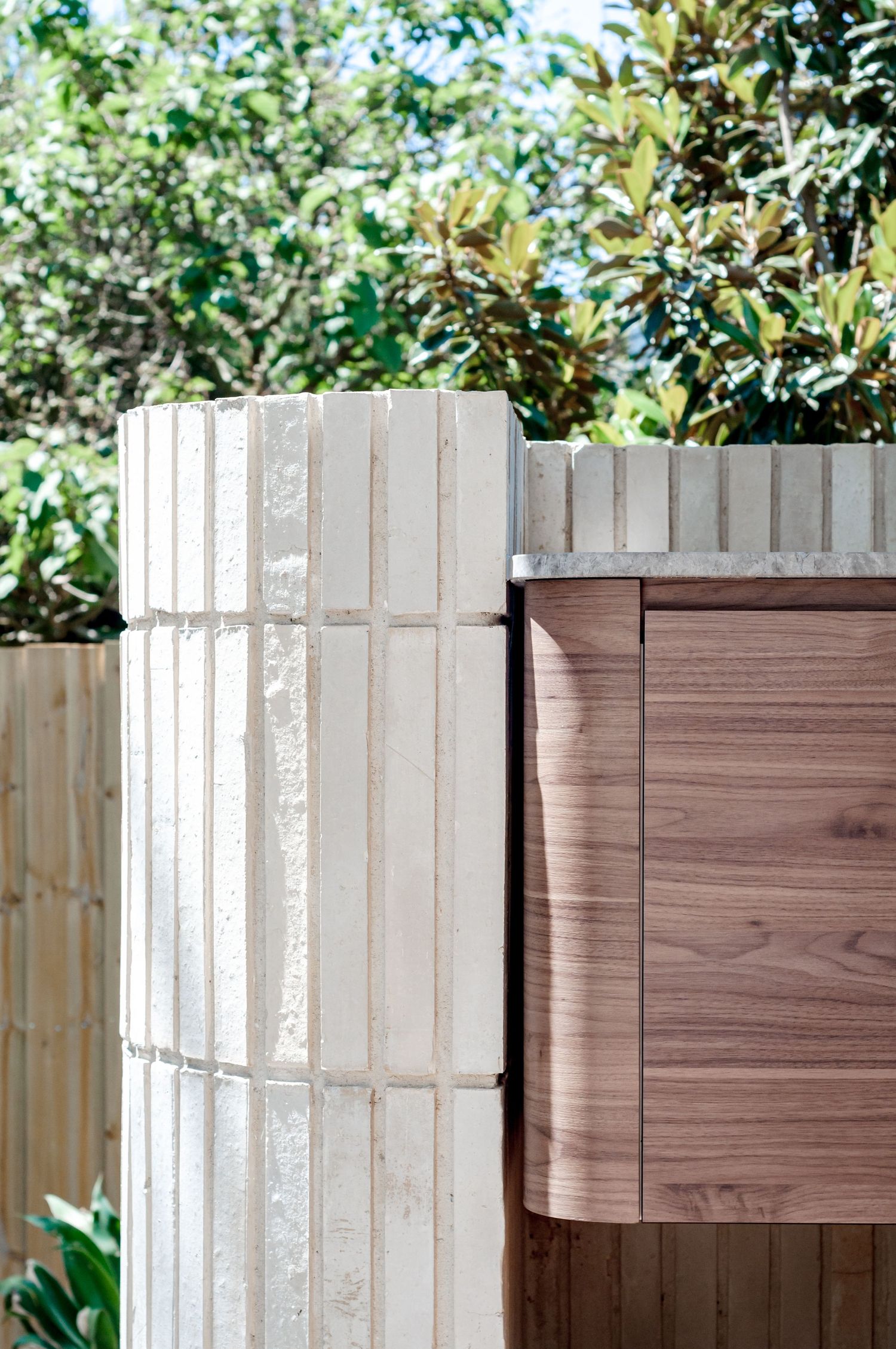 Contemporary exterior detail showing textured white wall panel next to wooden cladding.