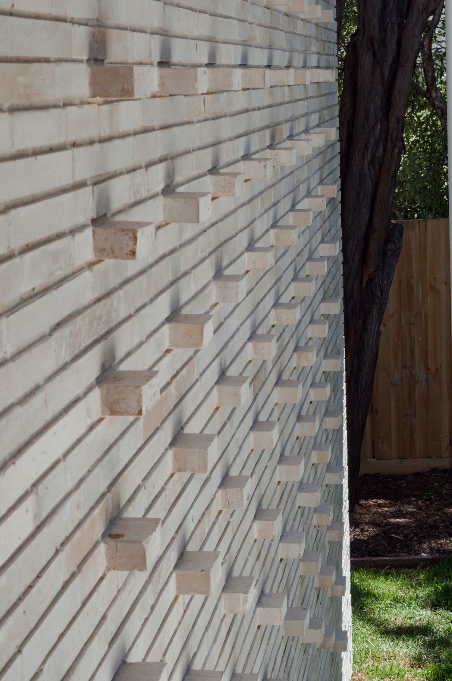 Detailed view of architectural wall showing textured brickwork with protruding elements in natural light.