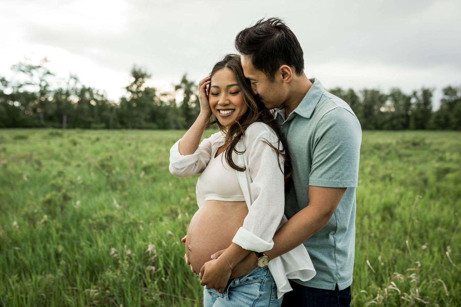Couple cuddling close during a windy outdoor maternity photography session in Calgary
