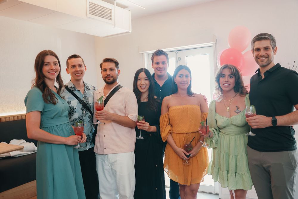 Group of friends gathered at a party wearing colorful outfits and holding drinks.