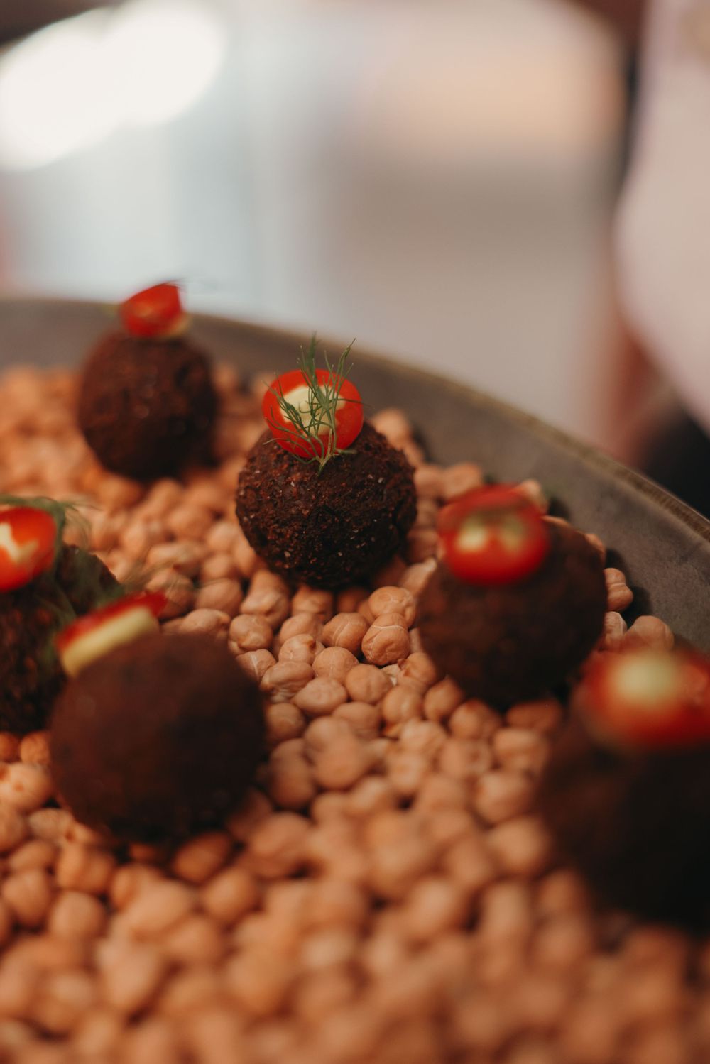 Chocolate truffles garnished with strawberries displayed on a bed of coffee beans.