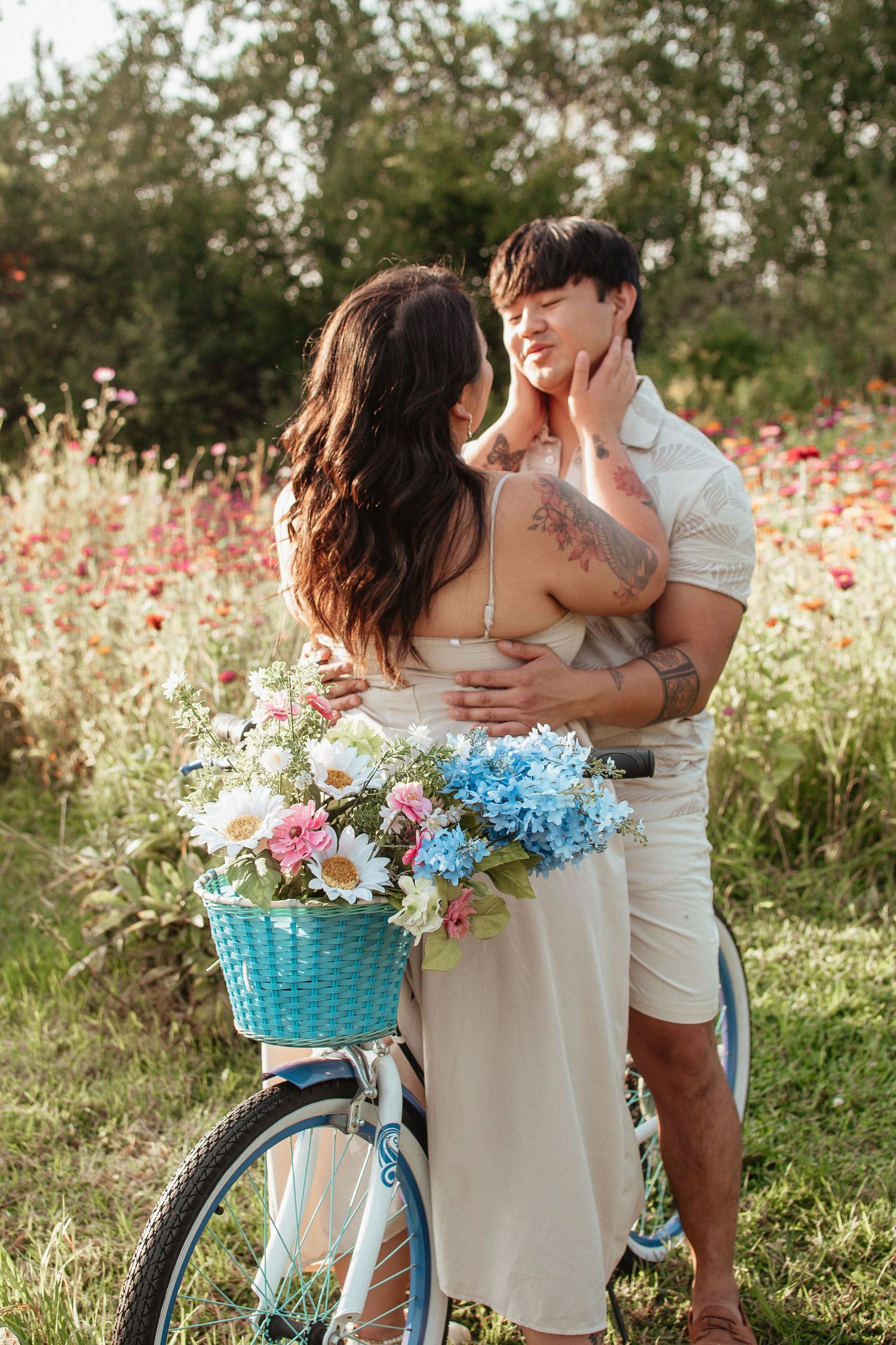 Romantic couple embracing near vintage bicycle with flower basket in summer meadow.