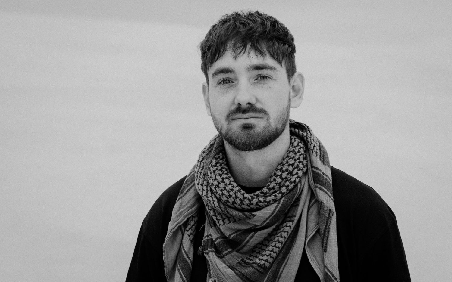 Black and white portrait of someone in a scarf and dark jacket.