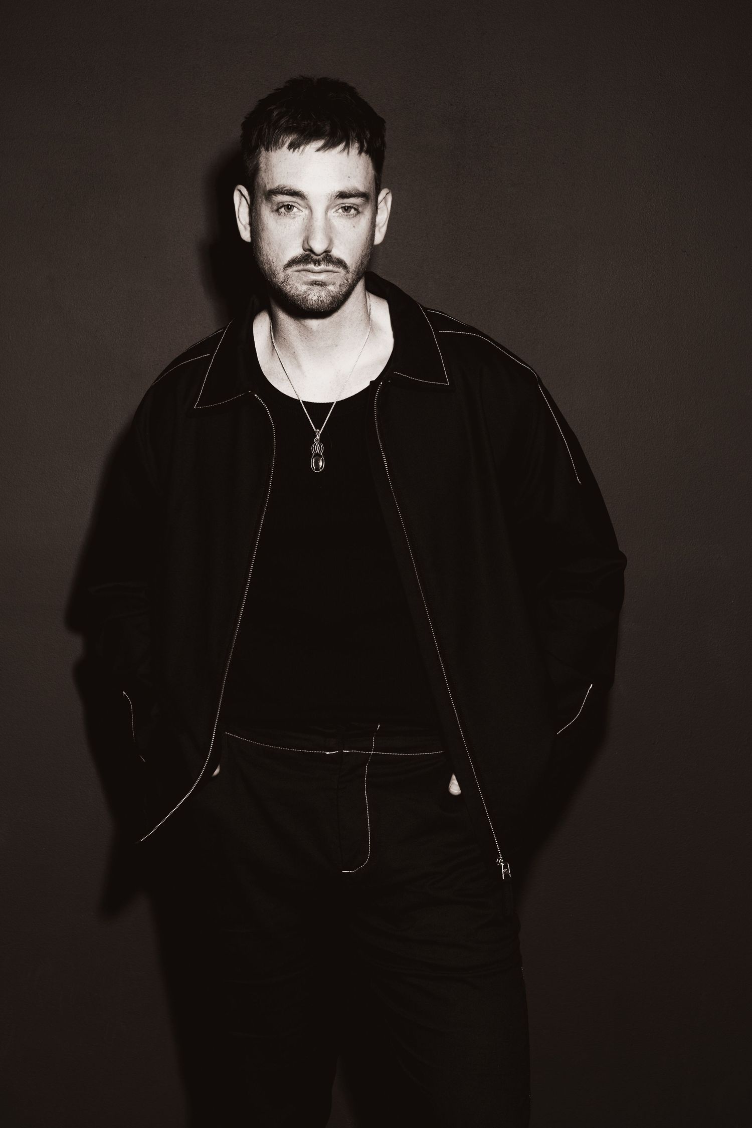Black and white portrait of someone in a scarf and dark jacket.