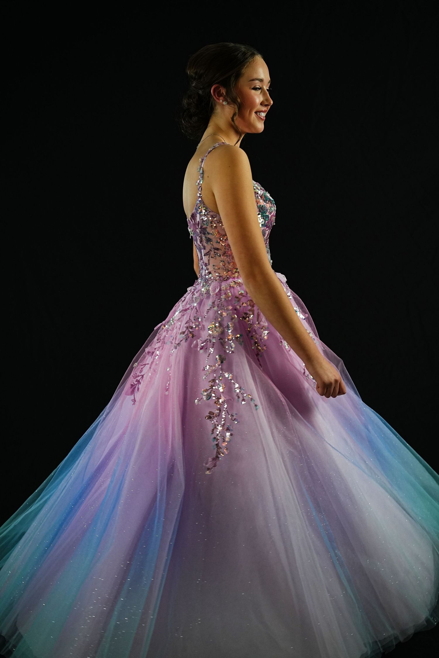 A graceful figure wearing a stunning pink and blue ombre ballgown with sparkling embellishments.