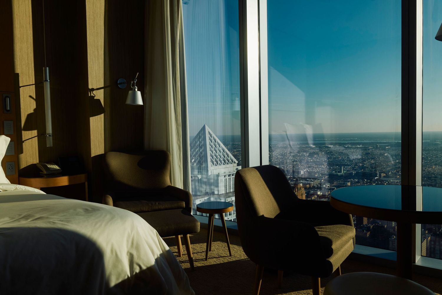Luxurious hotel room with panoramic city views through floor-to-ceiling windows.
