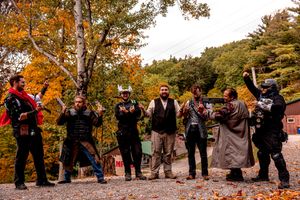 Group of LARP enthusiasts pose together on forest path during fall season.