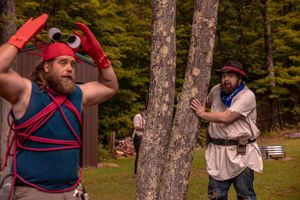 LARP participants practice combat moves between trees during autumn season.