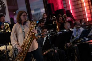 Jazz ensemble performs in a moody venue with woodwind and brass instruments.
