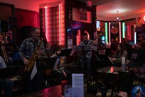 Musicians perform in a dimly lit jazz club with red ambient lighting.