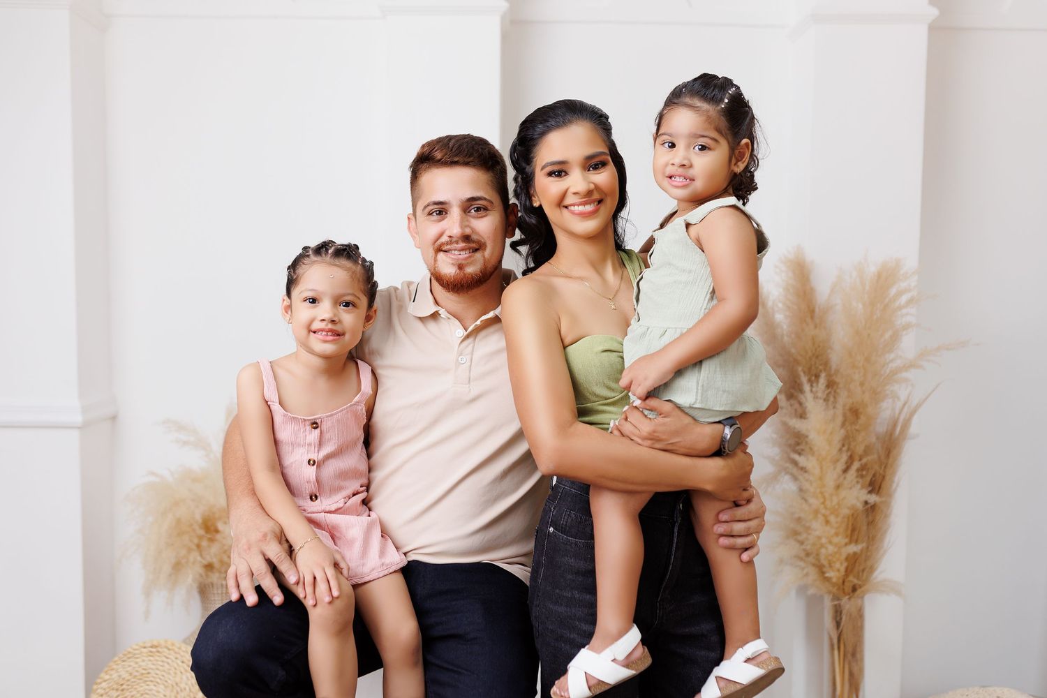 Family portrait session featuring parents and children in coordinated neutral tones against a white backdrop.