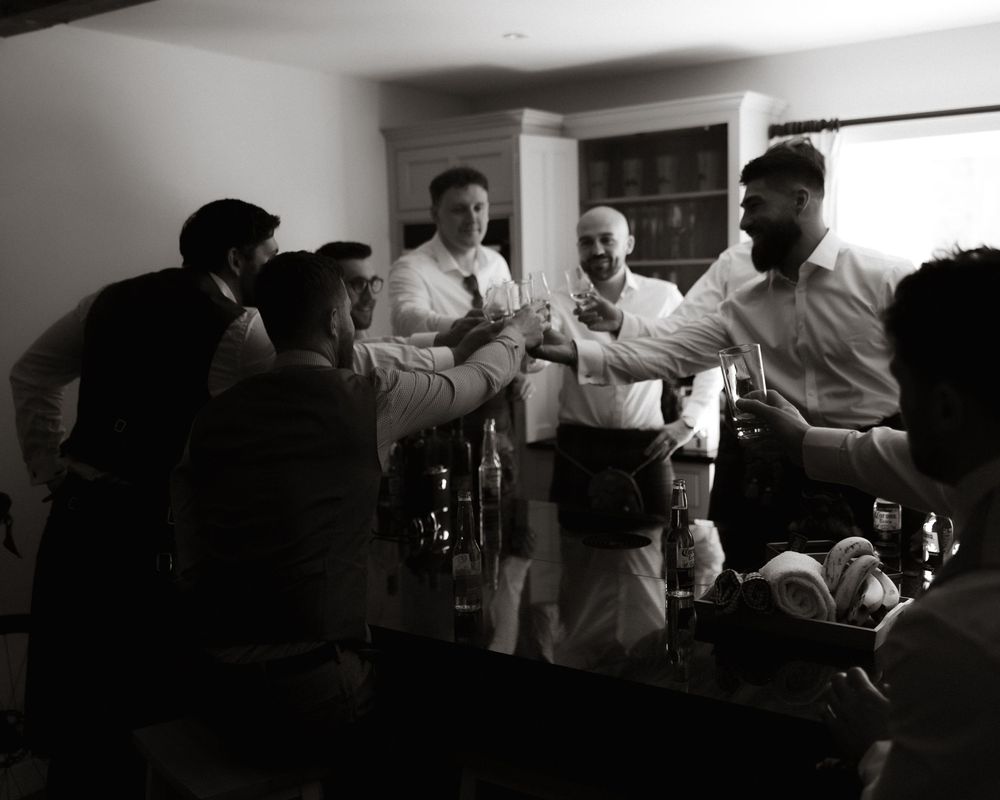 A group of men in formal attire toast and celebrate together in a black and white photograph.