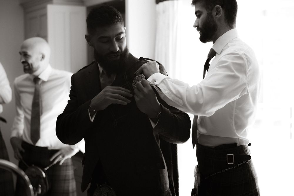 Two men in formal attire getting ready for an event in a black and white scene.
