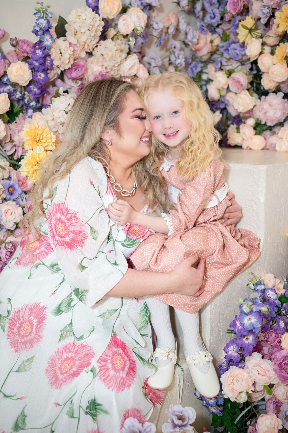 A loving portrait against a floral backdrop with pink and purple blooms during a spring photo session.