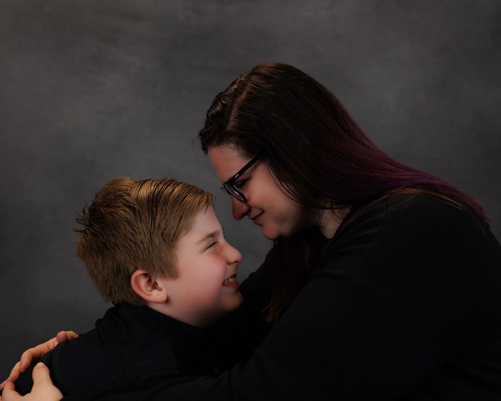 A joyful moment captured as two people share laughter while facing each other against a dark studio background.