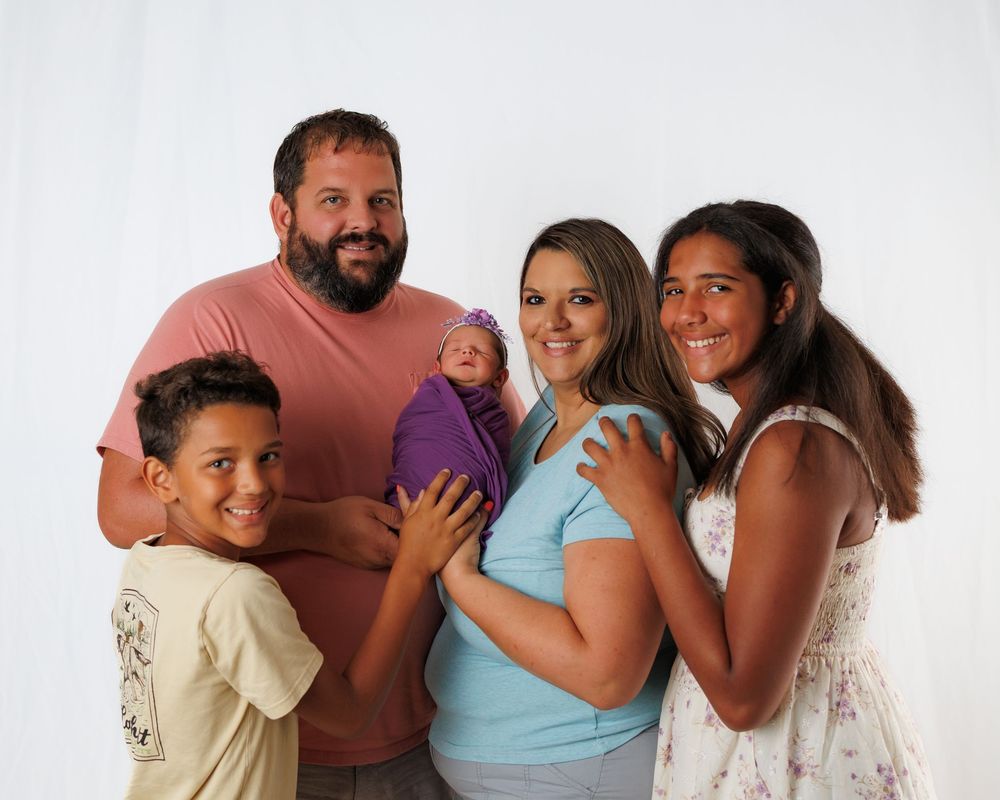 A group of people wearing casual clothing standing together and smiling during a bright photoshoot.