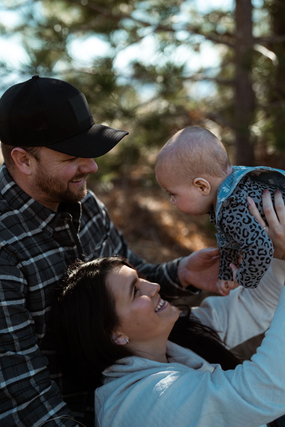 Young family enjoying tender moment together outdoors with infant among trees in natural setting.