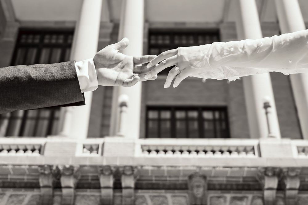Delicate hands of the bride and groom in front of the 1910 Harris County Courthouse in Houston, Texas.